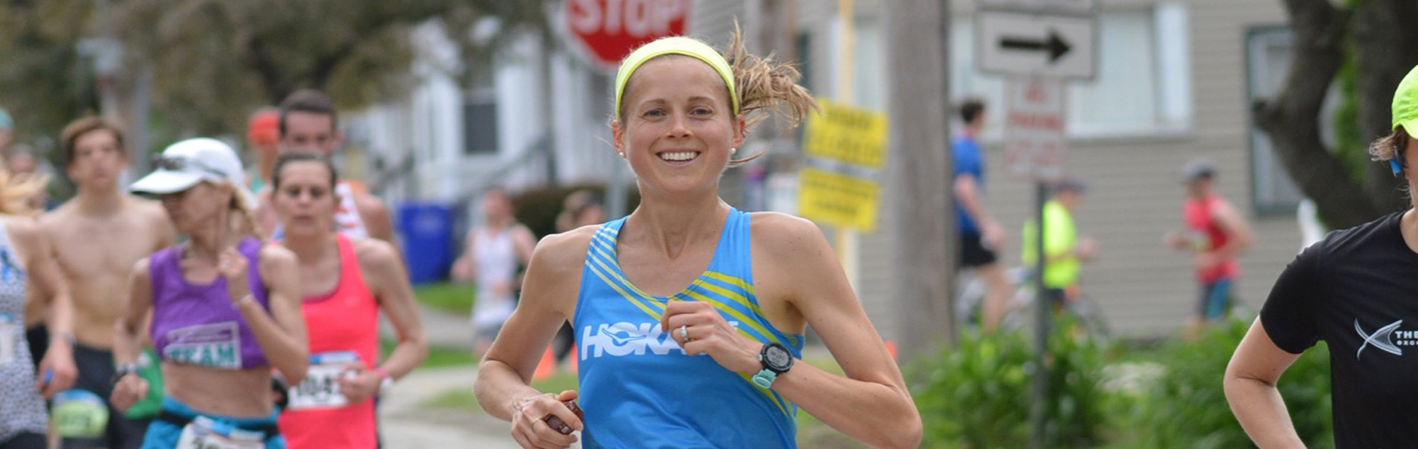 Smiling female runner in race with other runners in background