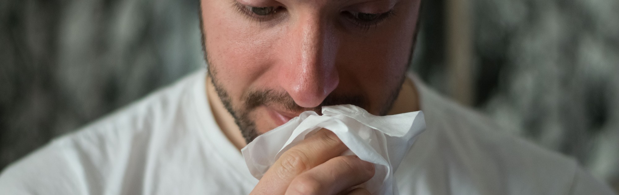 Bearded man with tissue in front of face